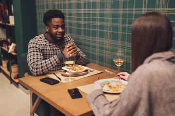 Two friends are having dinner at restaurant. They are sitting, talking and enjoying time together.