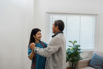 Fototapeta premium Happy Senior Couple Dancing Together at Home in a Bright Living Room with Natural Light and Cozy Atmosphere