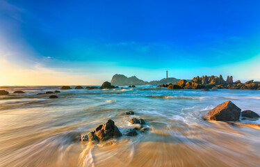 Beautiful Ke Ga Lighthouse in the morning with surf patted smoother reefs create clouds on sea as...