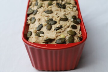 Whole Grain  Rye Sourdough Bread Dough with Seeds in a Red Loaf Pan
