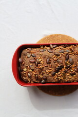 Whole Grain Rye Sourdough Bread Loaf with Seeds in a Red Loaf Pan
