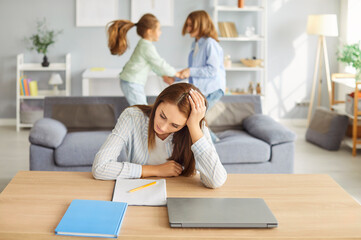 Young tired woman in noisy room, nanny, baby sitter single mother suffers from headache touching...
