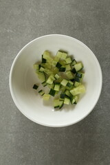 Diced green fresh cucumber in a white bowl.