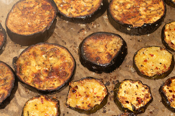 A roasted sliced seasoned aubergine eggplant courgette with salt and herbs cooked in the oven close up