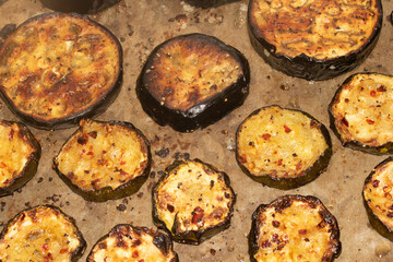 A roasted sliced seasoned aubergine eggplant courgette with salt and herbs cooked in the oven close up