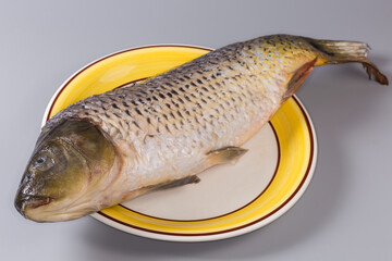 Big gutted grass carp cleaned from scales on large plate © An-T