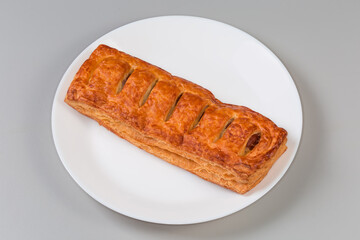 Whole baked easy sausage roll on a white dish