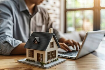 Fototapeta premium House Model in Close Proximity to Laptop on Desk