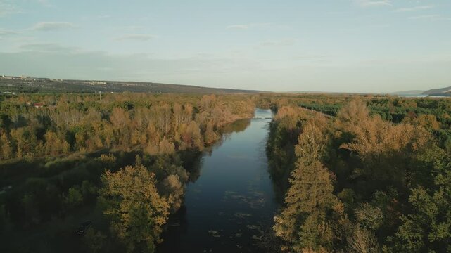 Calm river flows through autumn landscape at sunset