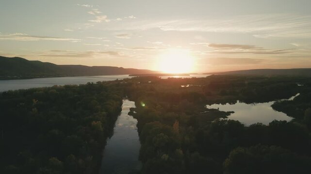 Golden sunset over calm river and lush forest landscape