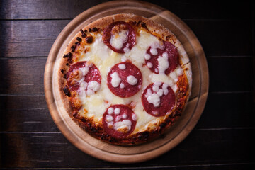 Pizza with salami and mozzarella cheese. Wooden background. Soft focus. Top view. Copy space. 	
