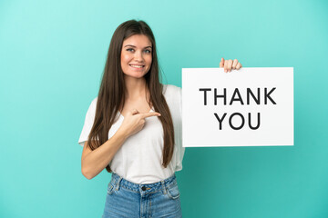 Young caucasian woman isolated on blue background holding a placard with text THANK YOU and ...
