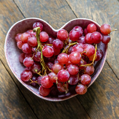 Looking down at a bunch of grapes in a heart shaped bowl