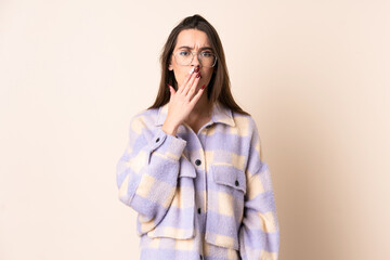 Young woman over isolated beige background yawning and covering wide open mouth with hand