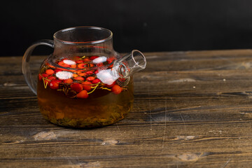 red rosehip fruits on a black tea table