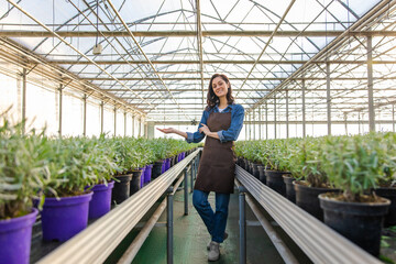 Pretty caucasian young woman standing in a greenhouse near the plants