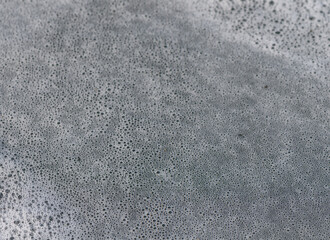 Unique patterns of foam on a rocky shoreline create a mesmerizing natural artwork at dusk