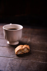 Cantuccini (Italian cookies) and a cup of coffee on dark wooden background. Close up..