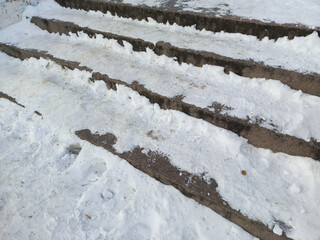 Snow on the stairs outside. Unpaved roads in the city. Asphalt in the snow. Slippery stairs. 