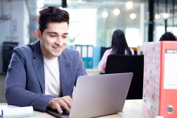 Young Manager Smiling While Typing On Laptop
