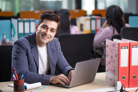 Deputy General Manager Sitting At Desk Smiling Looking At Camera
