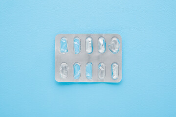 Opened empty blister pack without pills on light blue table background. Pastel color. Closeup. Top...