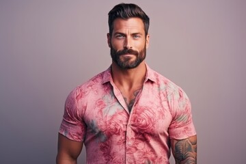 Fototapeta premium A man with a beard and tattoos is wearing a pink shirt