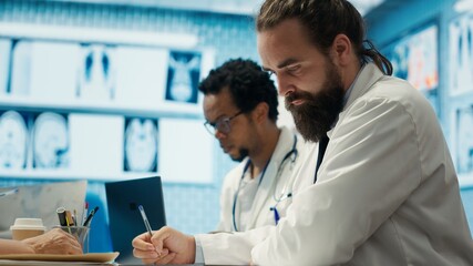 Obraz premium Physician writing a prescription for treatment plan at his cabinet desk, recommending medicine for disease prevention. Medic consulting analytics and hospital records in a clinic. Camera A.