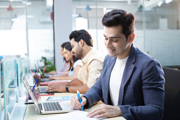 Small Business Consultant Working On Laptop Writing  Notes In His  Workplace