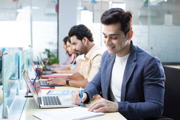 Organizational Consultant Writing Notes On Paper In Front Of Laptop