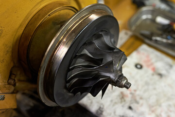 Close up of a compressor side of turbocharger assembly with blades covered in carbon soot deposits.