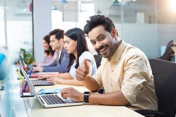 Office Peer Using Laptop And Gesturing Thumbs Up In Office