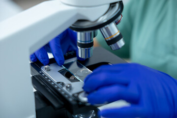 Unrecognizable female doctor in clinic focused on scientific study using microscope