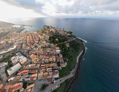 The historic town of Castelsardo in Sardinia, perched on a hilltop overlooking the sea, with colorful buildings and a dramatic coastal landscape.