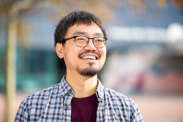 Fototapeta premium Close-up portrait of a happy Asian man looking up outdoors