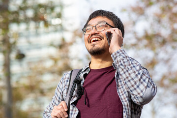 Taiwanese man using phone with a smile in an outdoor setting