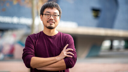 Portrait of an Asian man with arms crossed in an outdoor urban area