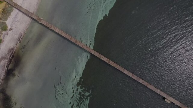 Top view of the wooden Port Neil jetty with the different colours in the clear water and a running couple