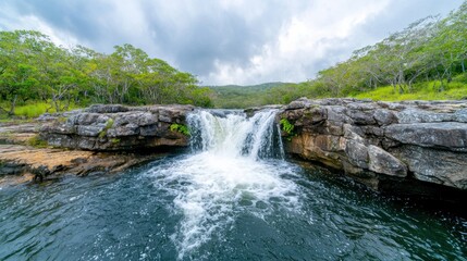 Fototapeta premium The waterfall is surrounded by lush greenery and cascades down the rocks with a soothing sound