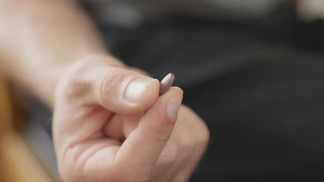 A focused shot of a hand holding a small, rounded object, emphasizing detail and clarity. The background is intentionally blurred to enhance the subject's emphasis and draw attention to the object.
