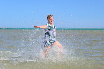 Happy woman splashing in ocean water, summer fun.