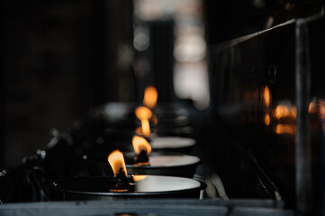 many candles in oil plate light up for people to offering or pray to buddha in Thai's temple