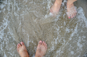 Fototapeta premium two feets of man and woman stand together on sand, abstract photograph, background, couple