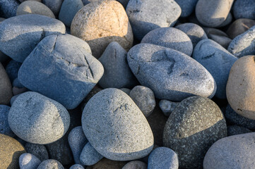 Natural assortment of smooth stones lying on a sunlit beach near the ocean