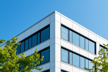 Obraz premium Modern architectural design featuring sleek building corner with large windows and greenery