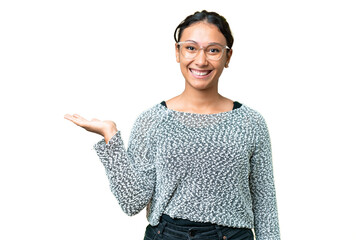 Young Uruguayan woman over isolated chroma key background holding copyspace imaginary on the palm...