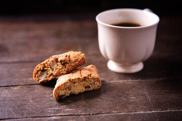 Cantuccini (Italian cookies) and a cup of coffee on dark wooden background. Close up..