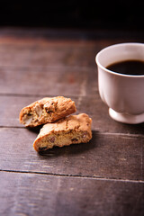 Cantuccini (Italian cookies) and a cup of coffee on dark wooden background. Close up.