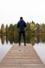 Man standing on pier at August in Finland during rain shower 