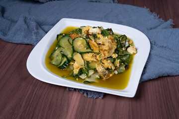 Scrambled eggs with cucumber on a white plate